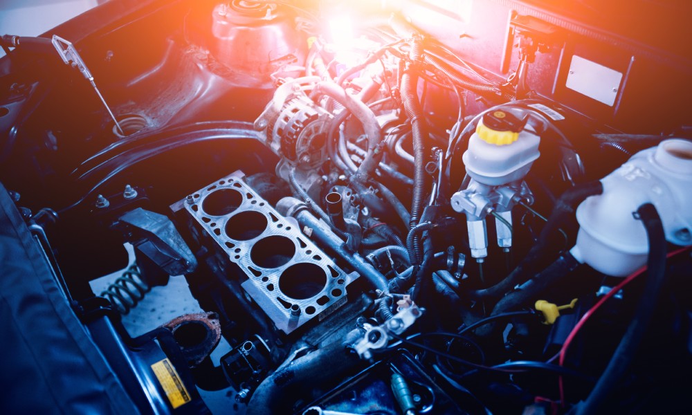 The view under the hood of a pickup truck revealing hoses, belts, and other engine components as well as loose auto tools.