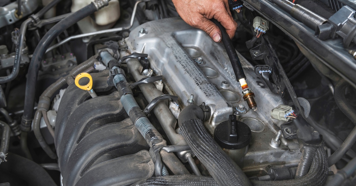 A close up view of a mechanic using a tool to work on spark plugs.