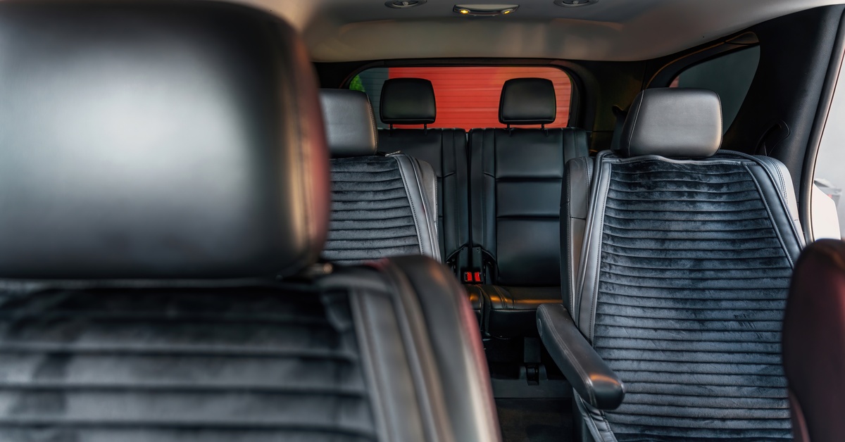 The interior of an SUV with two rows of passenger seats. The seats have a ribbed cushion design with vertical lines.
