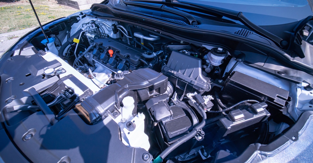 A car with the hood propped up to expose the intricate components in the engine bay, which is clean.