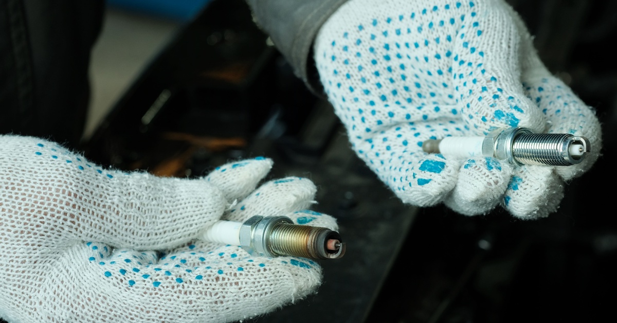 How To Tell if Denso Toyota Parts Are Authentic A person wearing white gloves holds a spark plug in each hand. One is shiny and new, and the other is worn and rusted.