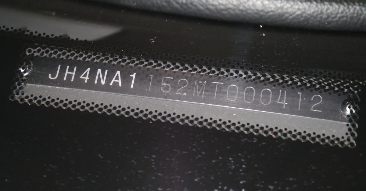 An extreme close-up of a vehicle identification number located on a textured black surface in a car.