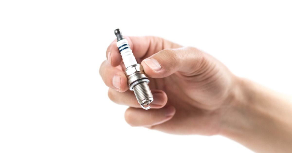 Denso Toyota Spark Plugs: Iridium Longevity Explained A person is holding a single iridium spark plug in their hand. The object is against a solid white background.